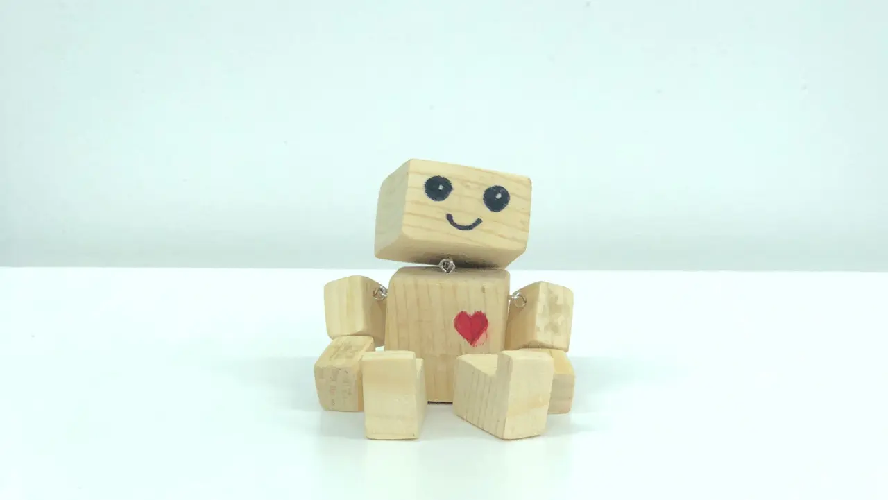 Sitzender Roboter aus Holz mit einem aufgemalten roten Herz