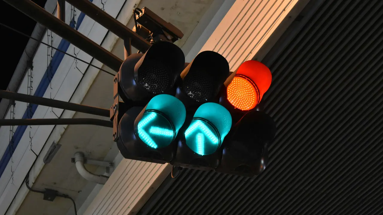 Ampelanlage mit zwei leuchtenden Grünpfeilen und einem roten Signal