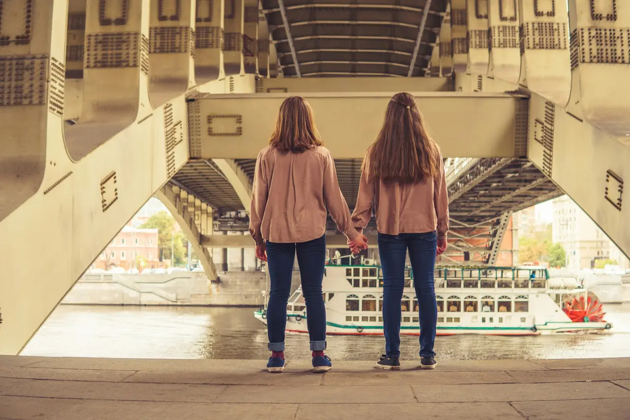 Zwei junge Frauen halten sich an den Händen und schauen in die Ferne.