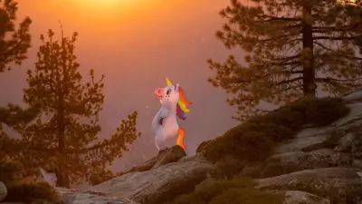 Eine Person in einem Einhornkostüm steht auf einem Felsen und Blickt der untergehenden Sonne entgegen.